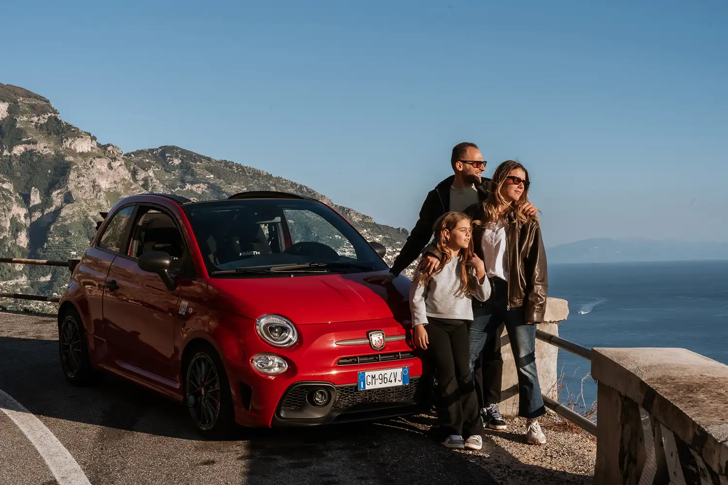 Family in a red Fiat 500 driving along the roads of the Amalfi Coast.