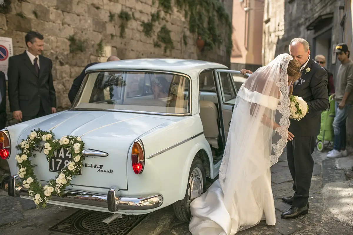 Bride with a vintage car on her wedding day.